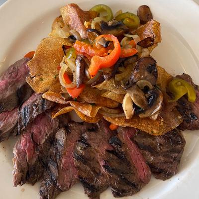 Sliced steak topped with crispy potato chips and colorful sauteed peppers, onions, and mushrooms.