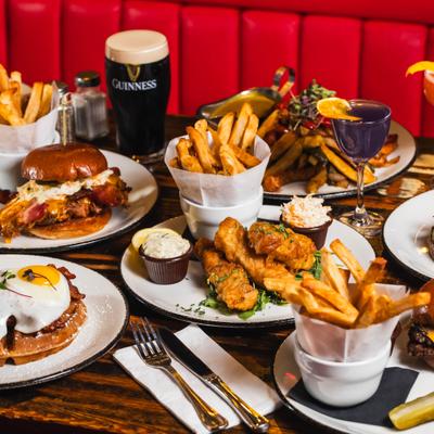 Assorted plated dishes, sides, and drinks spread across a wooden table.