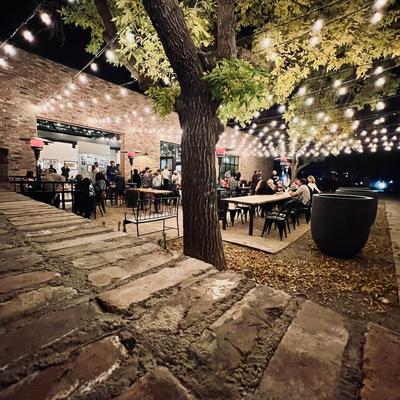 Night courtyard dining area with string lights and people seated.