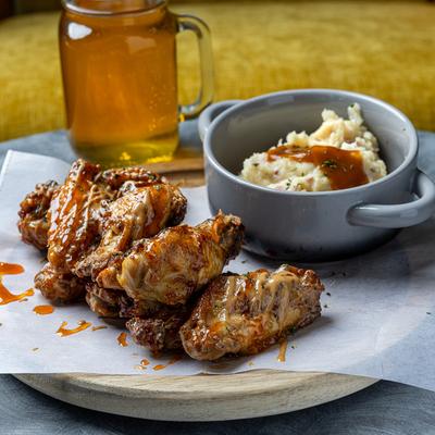 Chicken wings served with a side of mashed potatoes and a drink.