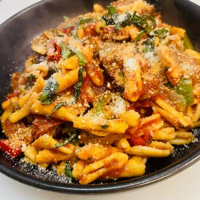 Pasta in tomato sauce with vegetables and grated cheese.