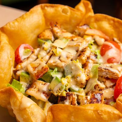 Chicken taco salad served in a large, crispy, edible tortilla bowl.