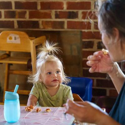 A toddler and an adult eating at a table.