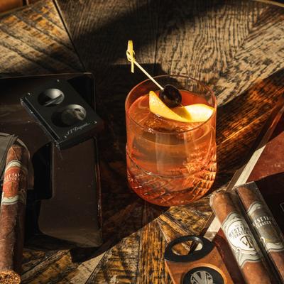 House Old Fashioned and cigars on a table with sunlight casting shadows