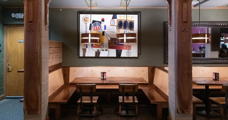 Interior,  seating area with wooden booths and painting on the wall