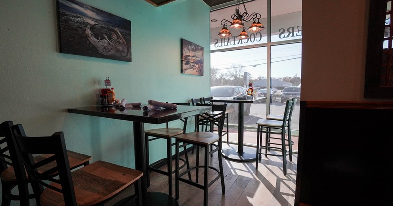 A restaurant interior with teal walls, a chandelier, and tables near a large window