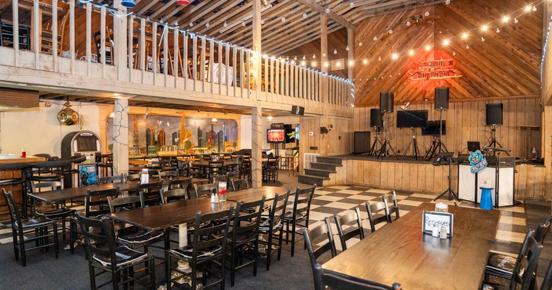 Inside, dining venue features wooden beams, string lights, and checkered floors, stage in the back