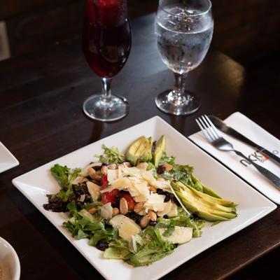 Salad of mixed greens, tomato, nuts, avocado slices and cheese.