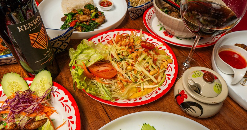 Papaya salad served alongside other dishes and red wine