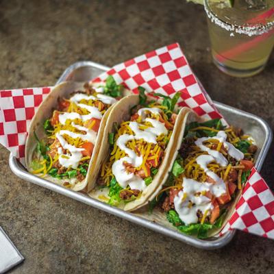 Three beef tacos on a metal tray.