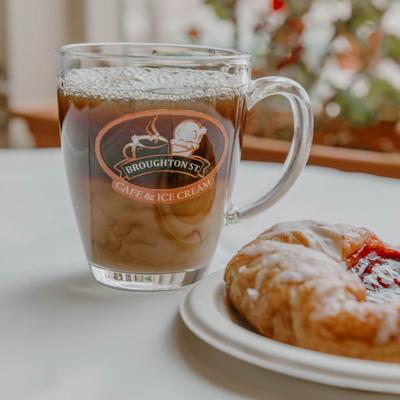 Cherry Danish on a white plate next to a glass mug of Iced coffee.