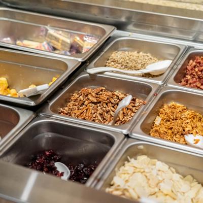 Salad bar metal bins with assorted toppings.