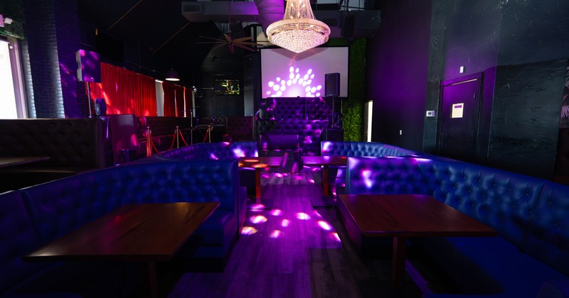 Interior, club area, booths,  purple light atmosphere,  video screen behind