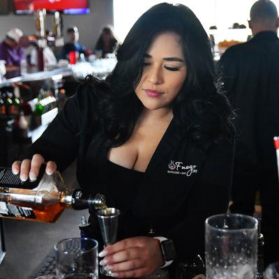 A bartender pouring liquor into a jigger.