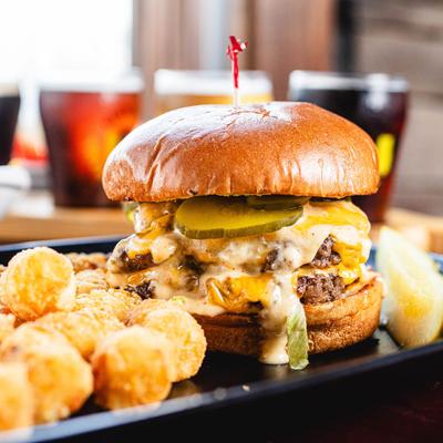 Double cheeseburger topped with melted cheese, pickles, and sauce, served with tater tots.
