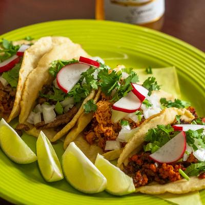 Tacos with various meats, onion, cilantro, and radish.