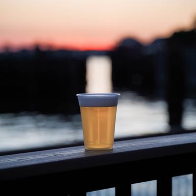 Glass of beer placed on a ledge during a sunset.