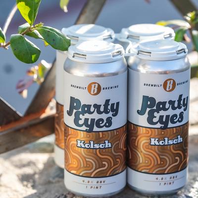 A four pack of Party Eyes Kolsch placed in an outdoor setting.