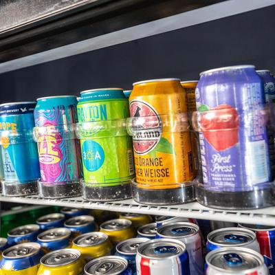 Colorful beer cans on a refrigerated shelf.