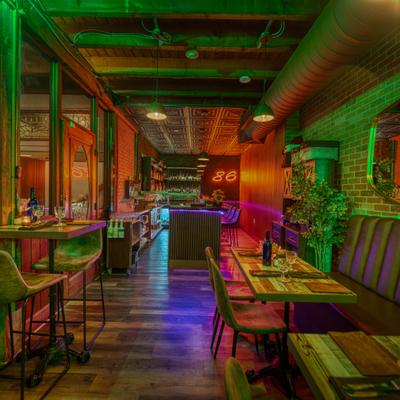 Interior with a mix of booth and high-top table seating, neon sign and decorations.
