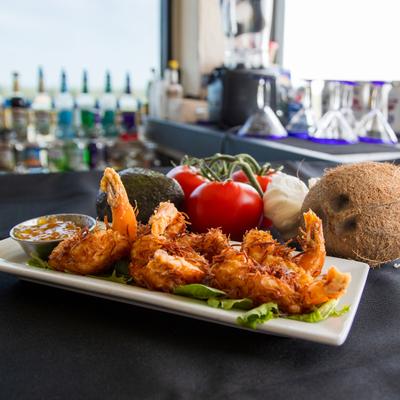 Coconut Shrimp served on a bed of lettuce with a dipping sauce on the side.