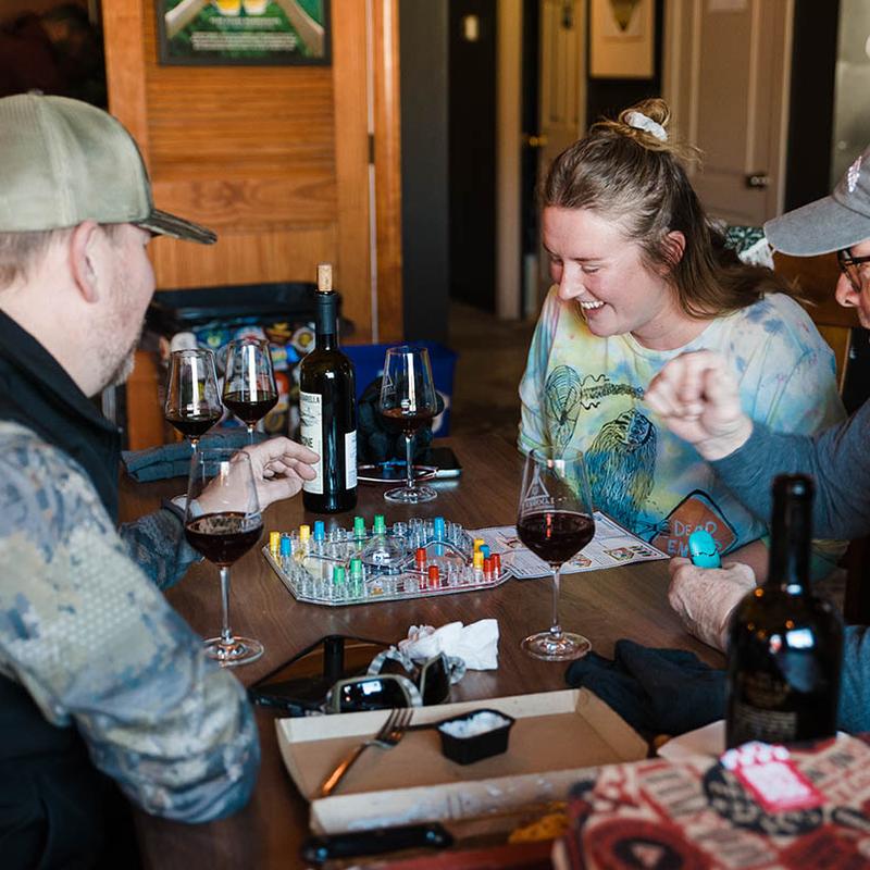 People enjoying a board game together while sipping red wine.