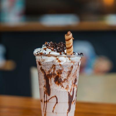 Oreo milkshake topped with whipped cream, chocolate drizzle, and a wafer stick.