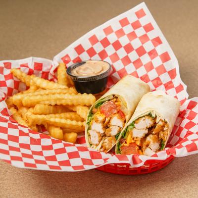 A basket with crinkle-cut fries and a chicken wrap on checkered paper..