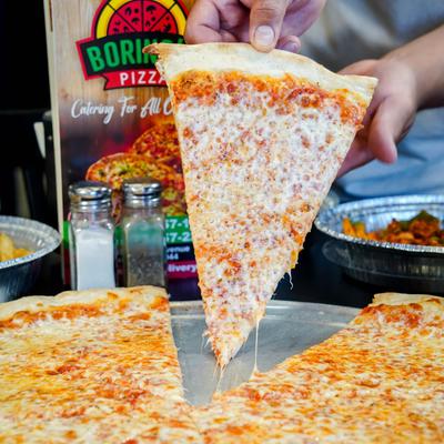 A cheese pizza slice is being lifted from the the whole pizza.