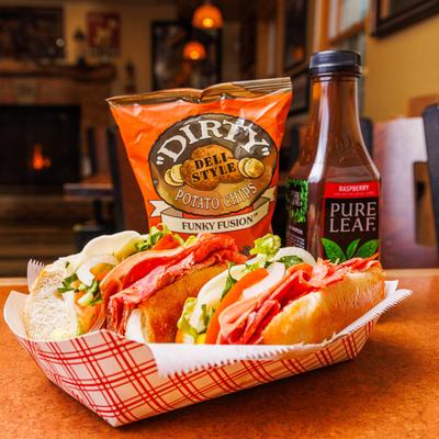 Italian sandwich with assorted meats, served with a bag of chips and raspberry tea.