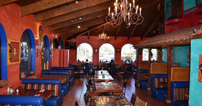 Interior,  dining area with red and blue walls, blue cushioned booths, and rustic chandeliers