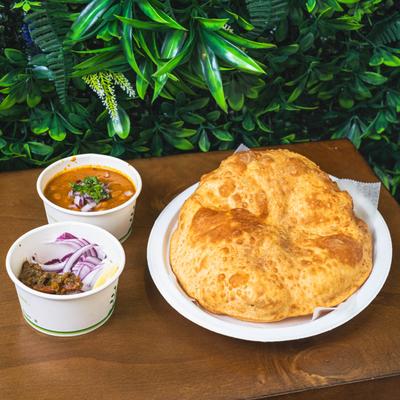 Indian chole bhature meal with puffy fried bread, chickpea curry, and onions.