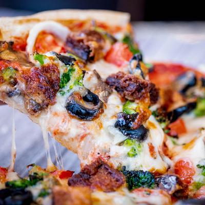 A slice of veggie pizza being lifted from the pie.