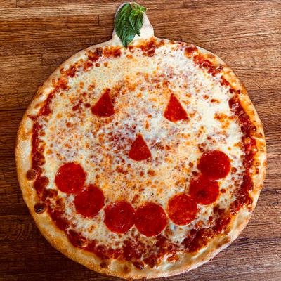 Pepperoni pizza with a Halloween-themed face design.