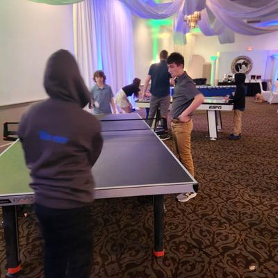 Children playing table tennis in an indoor event space.