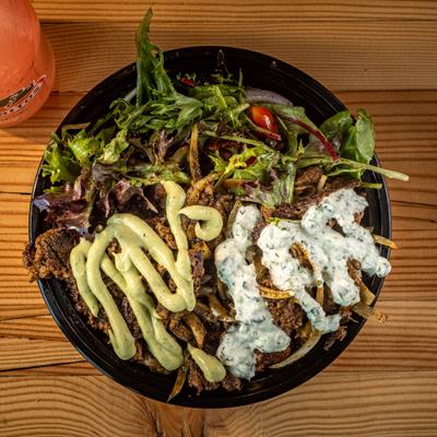 Faithful Feast bowl featuring grilled steak strips served over a salad, topped with sauces.