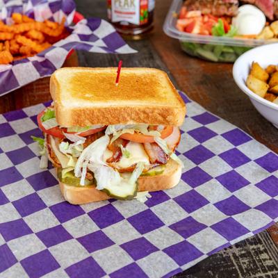 Grilled Club served on a purple and white checkered paper liner.