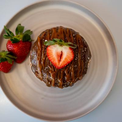 A chocolate-glazed dessert with caramel drizzle and a halved strawberry on top.