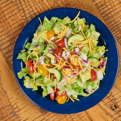 A vibrant salad - lettuce, cucumber, cherry tomatoes, red onions and cheese on a blue plate