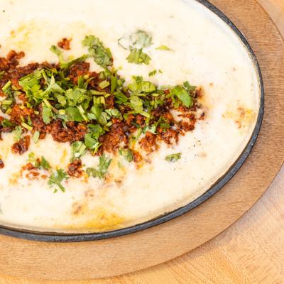 Cheese dip toped with meat and served in hot ast-iron skillet.