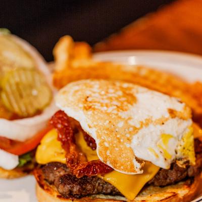 Cheeseburger topped with a fried egg and bacon, served with crinkle-cut fries.