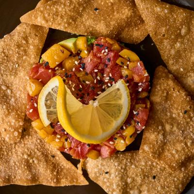 Tuna tartare with chips and lemon slices.