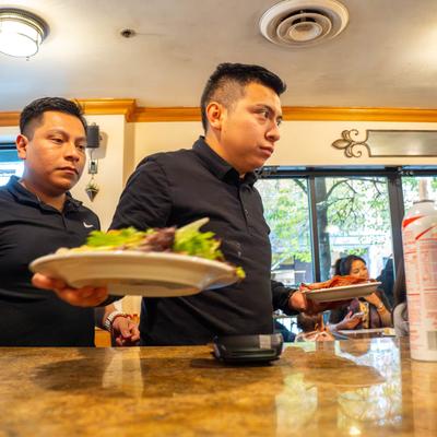 Two servers carrying plates of food.