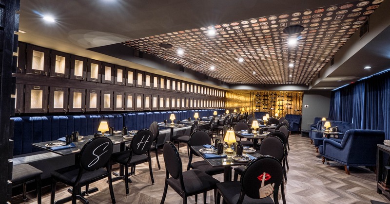 An elegant dining area featuring blue banquettes, black tables, and chairs