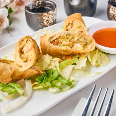 Crispy egg rolls with vegetables and dipping sauce.