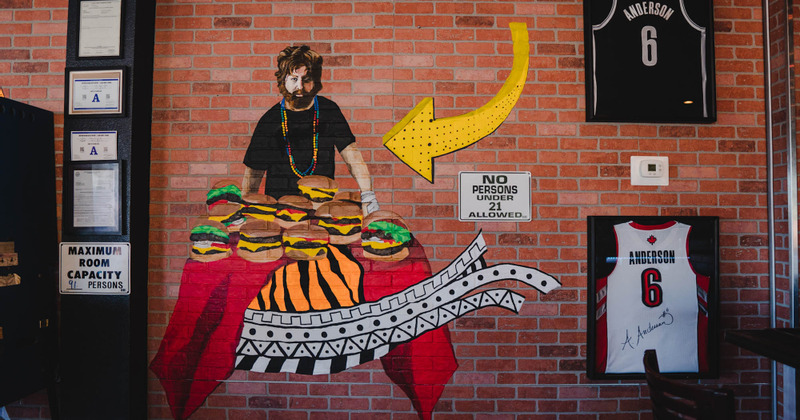 Mural of person presenting pile of hamburgers