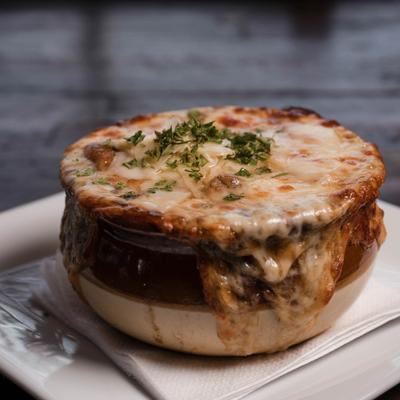 French onion soup served in a traditional brown ceramic crock.