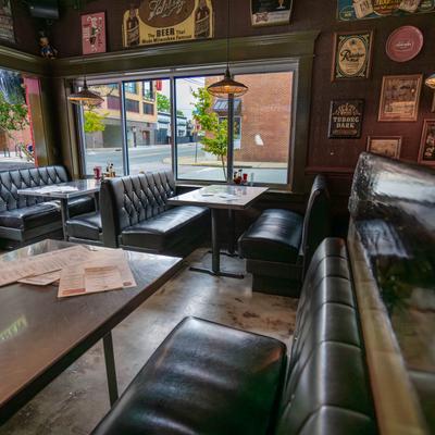 Interior with leather booths, tables, and vintage beer memorabilia on the walls.