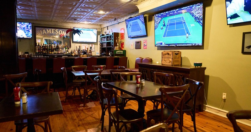 Interior, seating area with few large TV screens and a bar in the back