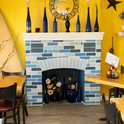 Blue tiled fireplace inside a dining room with a yellow wall.